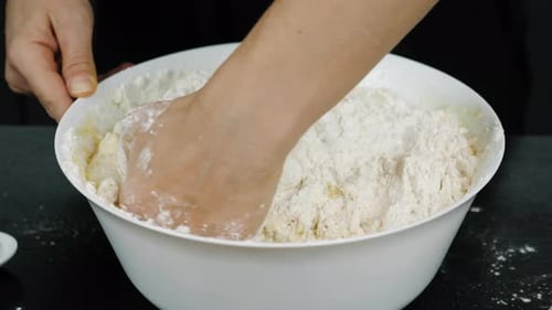 Hand Mixing Dough in White Bowl
