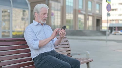 Senior Man Using Phone on Park Bench