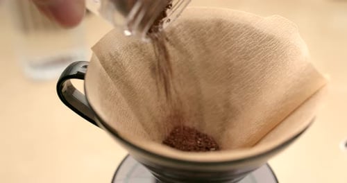 Pouring Fresh Coffee Grounds into Paper Filter