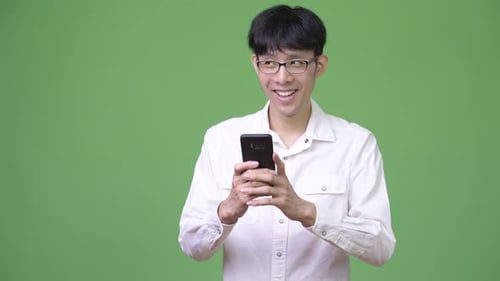 Young Adult Smiling at Smartphone against Green Background