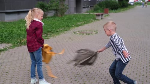 Back to School Children Playing on Street Blonde Boy and Girl Spinning with Backpacks