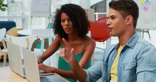 Colleagues Collaborating on Laptops in Bright Office