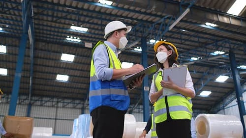 Warehouse manager discuss with his team during other staffs work in background for management