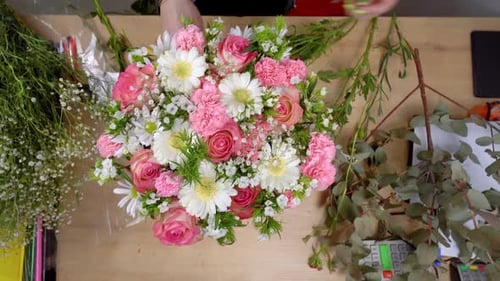Vue de dessus des mains d'une jeune fleuriste créant une composition