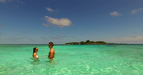 Romántica pareja de vacaciones de luna de miel pasa tiempo de calidad en la playa sobre un fondo soleado de arena blanca 4K