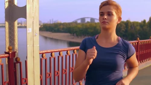 Woman Jogging on Bridge in City During Daytime