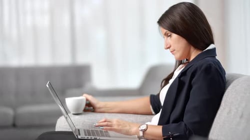 Woman Working on Laptop with Coffee at Home