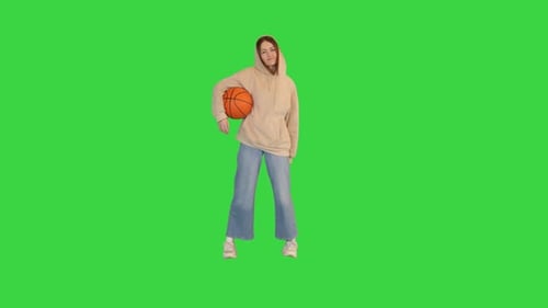 Young Girl Holding a Basketball Looking on Camera on a Green Screen Chroma Key