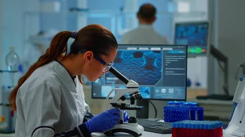 Wissenschaftler betrachten biologische Proben unter dem Mikroskop und tippen auf dem PC
