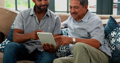 Young Adult and Senior Adult Use Tablet on Couch