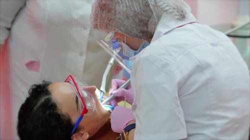 Woman Dentist Treating Teeth To Woman Patient in Clinic. Female Professional Doctor Stomatologist at