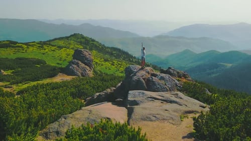 Tourist Woman Stands on a Rock with Arms Raised at an Altitude of 1700m