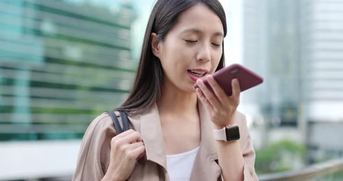 Smiling Young Woman Uses Phone in City