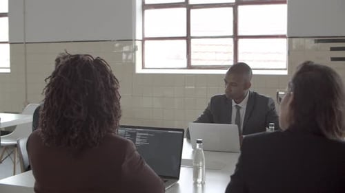 Business Meeting Around Table with Laptops and Water