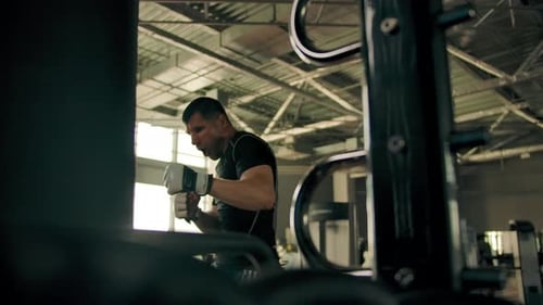Male in a Sportswear Hitting Hard on the Punching Bag in the Gym