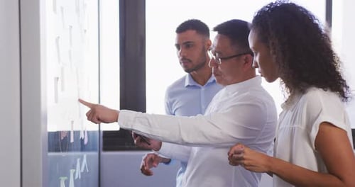 Senior Geschäftsmann mit digitalem Tablet diskutiert mit jungen Geschäftsleuten über Memo-Notizen