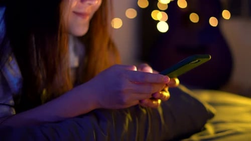 Young Adult Using Smartphone in Cozy Room at Night