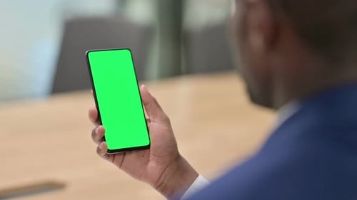 Close up of hand holding phone with green screen