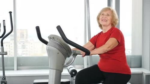Senior Woman Exercising on Bicycle Machine at Gym