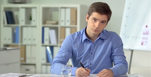 Thoughtful Young Adult Writing in Office Environment