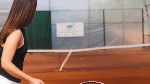 Brunette Woman Hitting the Ball on the Tennis Court Above the Net