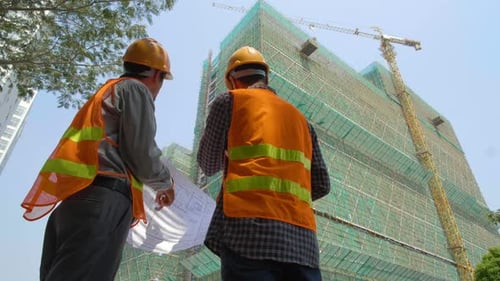 Engineers Discussing Construction Blueprint at Building Site