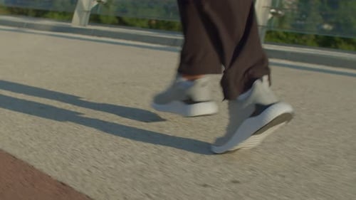 Rear View of Male Athlete in Sports Shoes Running on City Street at Daybreak