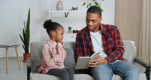 Man Reads to Child on Couch Indoors