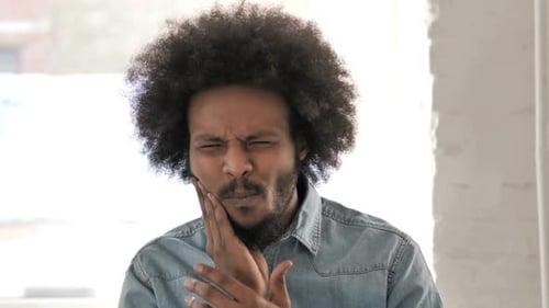 Jeune homme africain souffrant d'une infection dentaire
