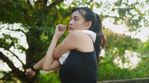 Happy Asian woman running in park on public green background,