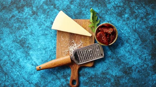Fromage parmesan râpé et râpe classique en métal posée sur une planche à découper en bois