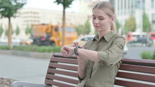 Woman Uses Smartwatch on City Park Bench