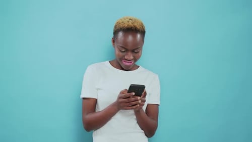 Smiling Woman Using Phone in Front of Blue Background