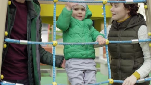 Junge klettert auf Spielplatz und Eltern bewachen ihn