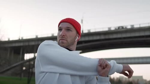 Young Adult Stretches Arms in Urban Park