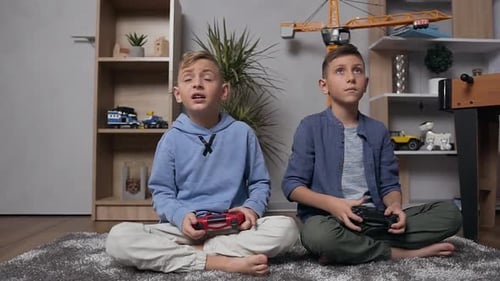Jungen, die auf dem Teppich sitzen und Videospiele mit Gamepads spielen
