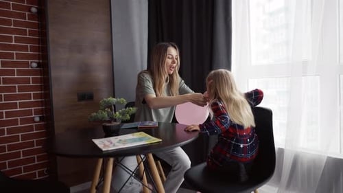 Woman Inflating a Balloon with Little Girl Watching