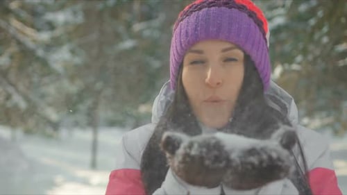 Woman Laughing Blowing Snow in Snowy Winter Forest