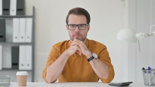 Young Man Thinking at Desk in Office