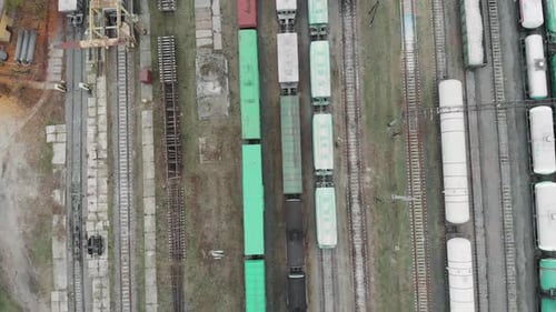 Voando acima de vagões de trem de carga carregados saindo da estação ferroviária industrial com contêineres