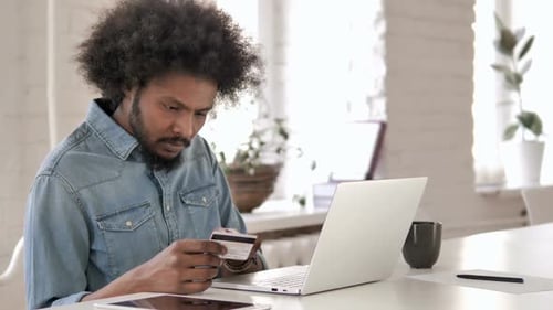 Man Using Credit Card and Laptop Indoors