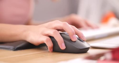 Hands typing on computer keyboard and use of mouse in office
