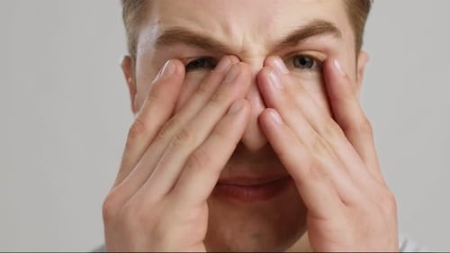 Man Rubbing Face in Discomfort
