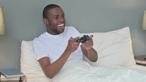 Young Adult Plays Video Games in Bed, Wins