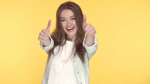 Smiling Woman Gives Two Thumbs Up on Yellow