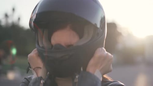 Young Woman Puts On Motorcycle Helmet for Ride