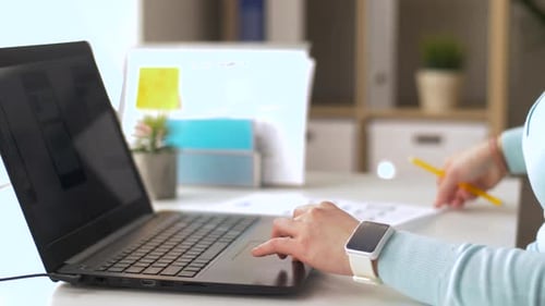 Woman Works at Desk with Laptop and Papers