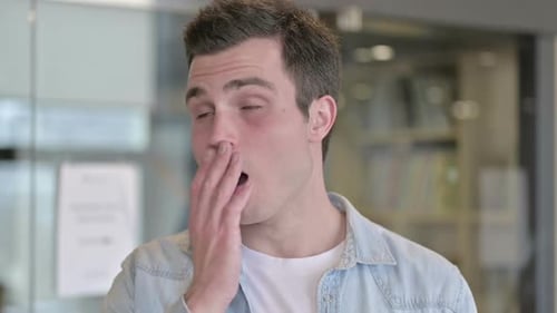 Portrait of Sleepy Young Male Designer Yawning in Office
