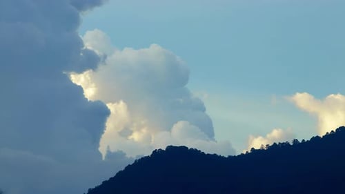 Puffy Cumulus Clouds Swirl at Sunset Over the Mountain