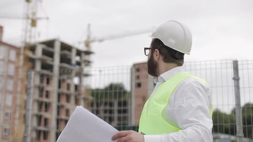 Engineer Inspecting Building Plans at Construction Site